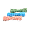 Three textured chew toys in pink, blue, and green rubber, arranged side by side on a white background.
