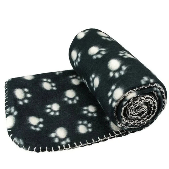 Rolled black pet blanket featuring a whimsical white paw print design, made of soft fleece material.